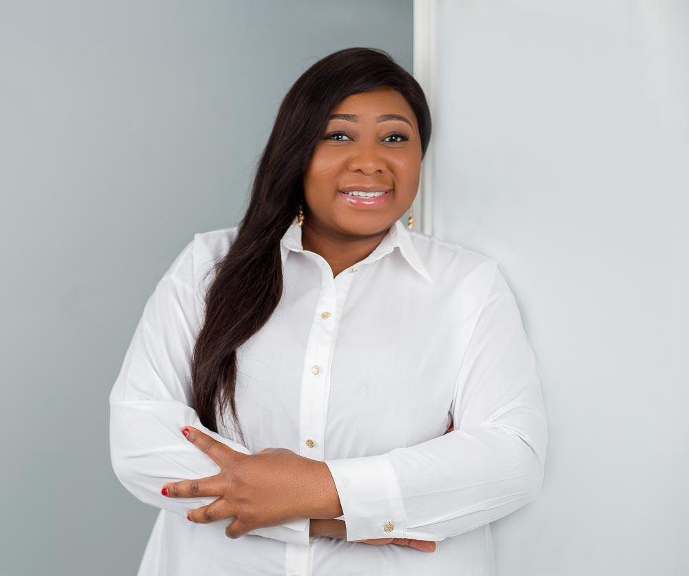 Pamela Femi-Ojo in a white shirt, arms folded, smiling